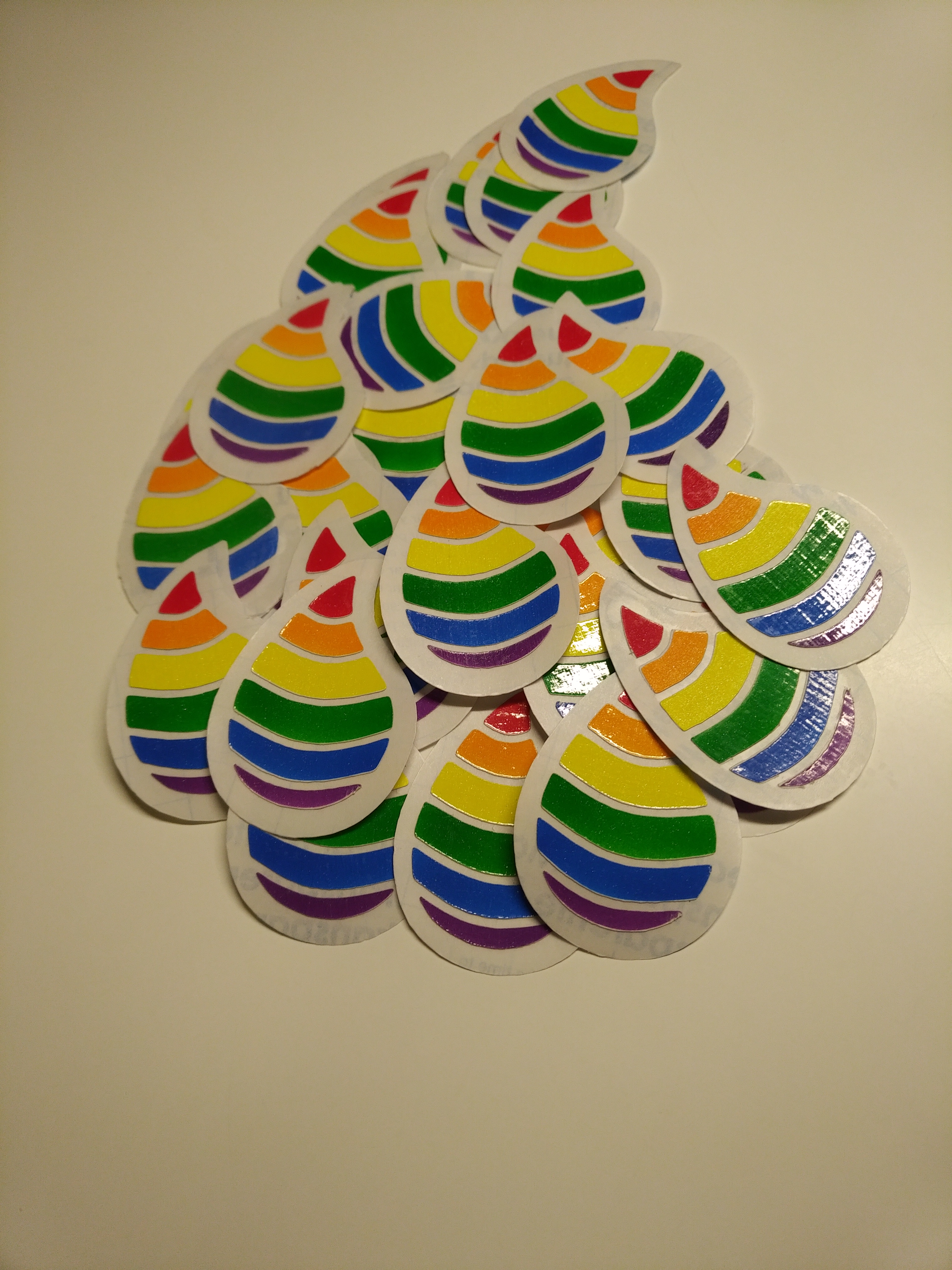 a pile of rainbow elixir droplet stickers with transparent border in the shape of a droplet